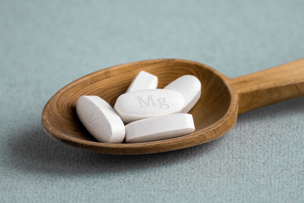 magnesium supplements in a wooden spoon